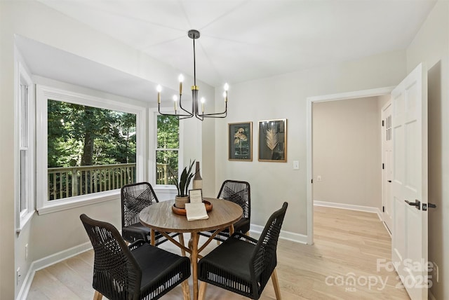 dining area with light wood-type flooring and a chandelier