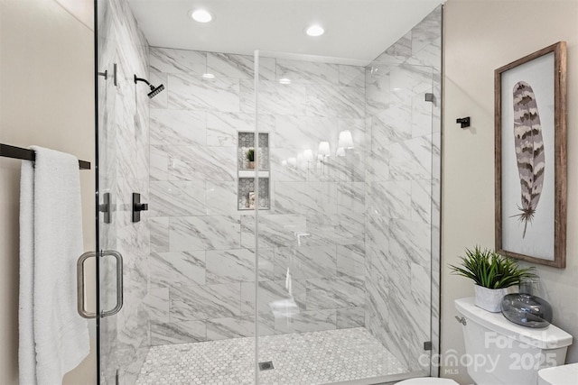 bathroom featuring a shower with shower door and toilet