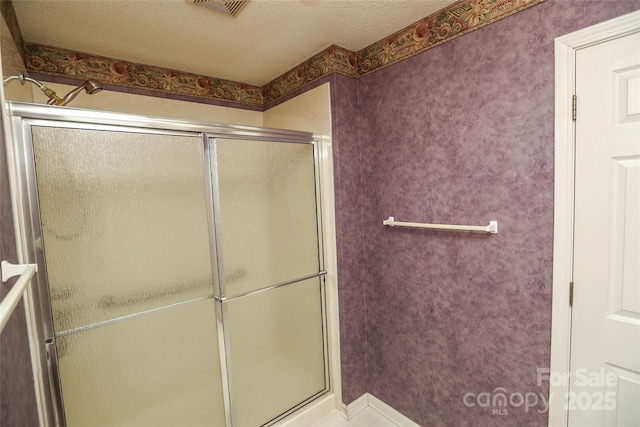 bathroom with a shower with door and a textured ceiling