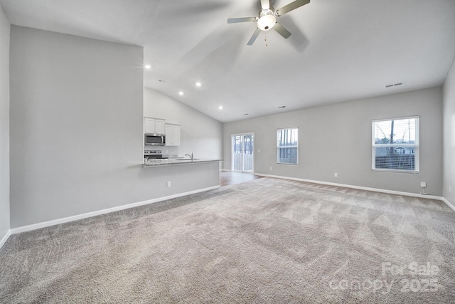 unfurnished living room featuring light colored carpet, plenty of natural light, lofted ceiling, and sink