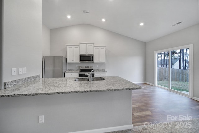 kitchen with kitchen peninsula, appliances with stainless steel finishes, vaulted ceiling, sink, and white cabinets