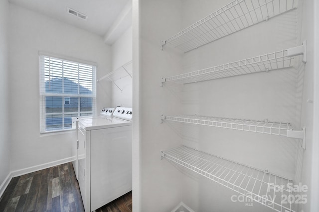 clothes washing area featuring washer and clothes dryer and dark wood-type flooring