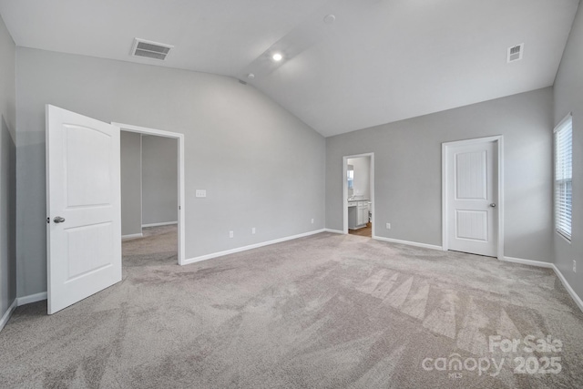 spare room featuring light colored carpet and lofted ceiling