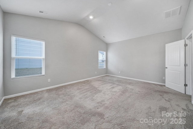 carpeted empty room featuring lofted ceiling