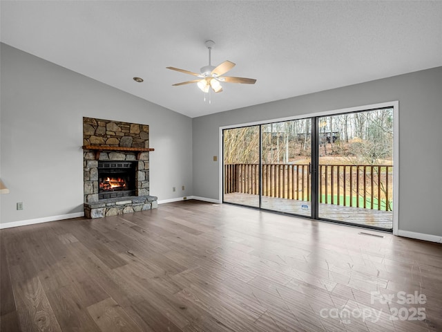 unfurnished living room featuring ceiling fan, wood-type flooring, lofted ceiling, and a fireplace