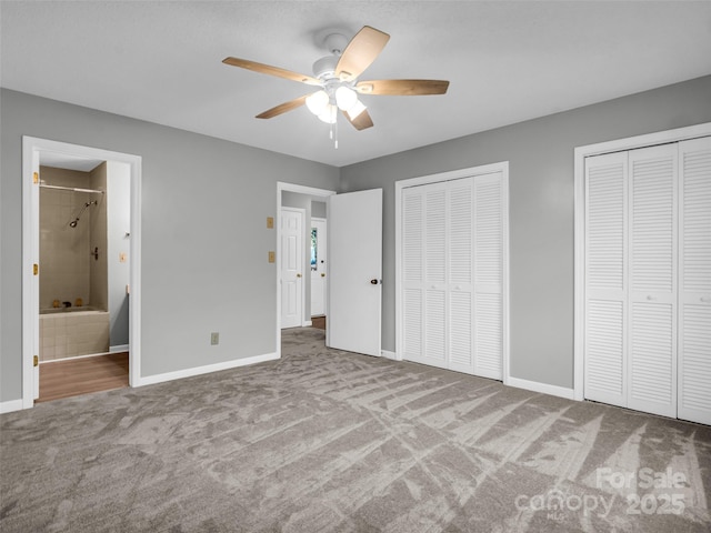 unfurnished bedroom with carpet, connected bathroom, ceiling fan, and multiple closets