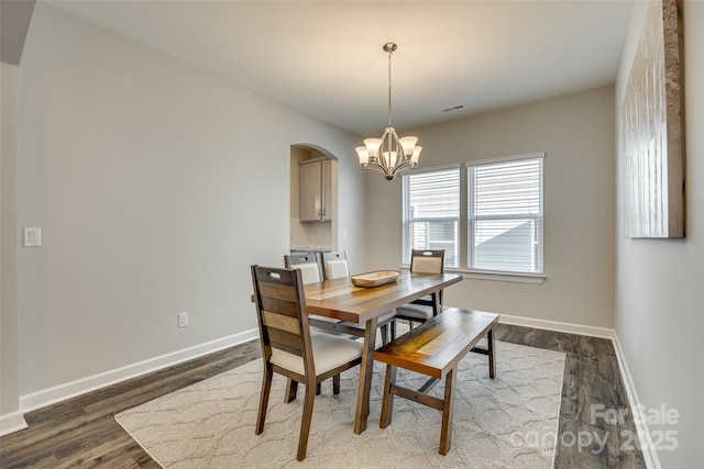 dining space with dark hardwood / wood-style flooring and an inviting chandelier