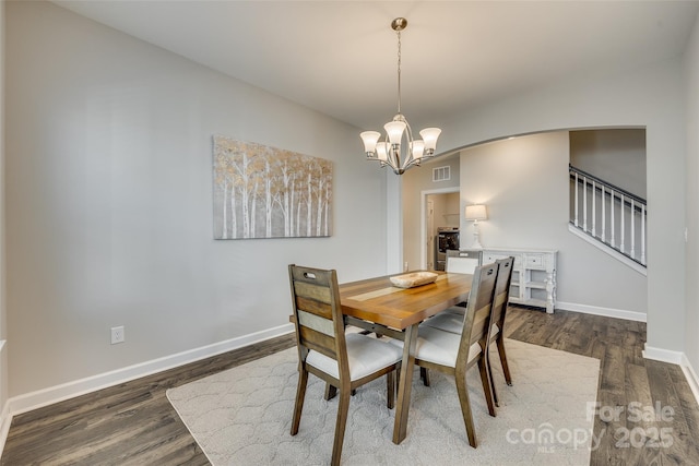 dining area with dark wood-type flooring and a notable chandelier