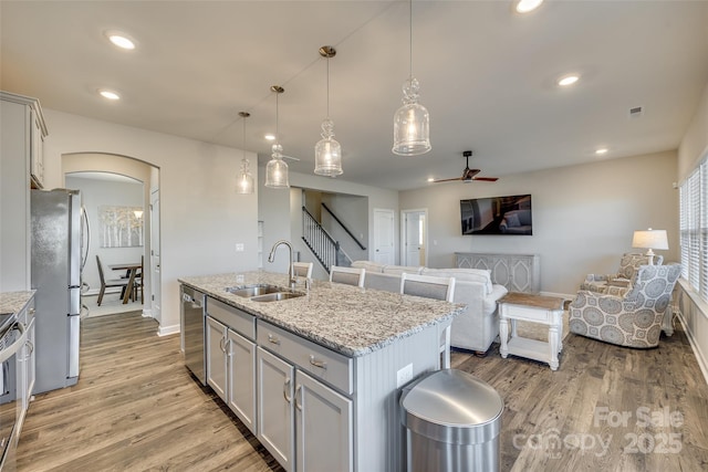 kitchen featuring appliances with stainless steel finishes, ceiling fan, sink, pendant lighting, and an island with sink