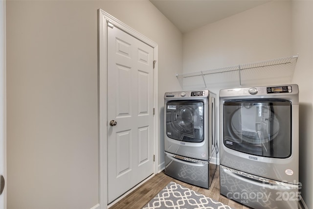 clothes washing area with hardwood / wood-style flooring and washer and dryer