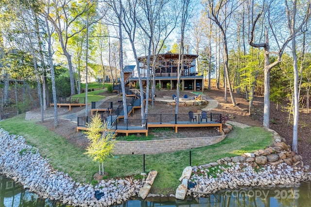 back of house featuring a deck with water view and a yard