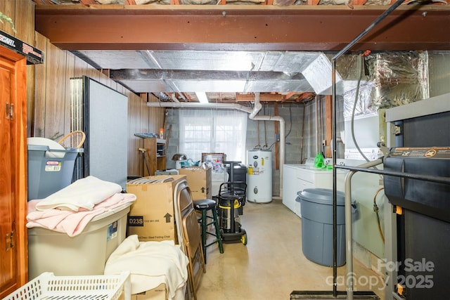 basement featuring washer and dryer, wood walls, and water heater