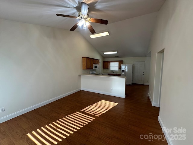 kitchen featuring lofted ceiling, dark hardwood / wood-style floors, kitchen peninsula, ceiling fan, and fridge with ice dispenser