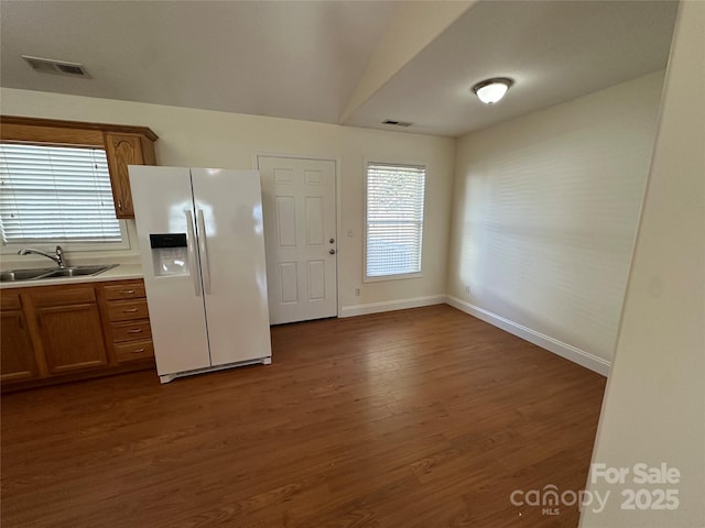 kitchen with dark wood-type flooring, sink, and white fridge with ice dispenser