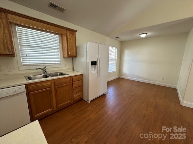 kitchen with vaulted ceiling, dark wood-type flooring, sink, and white appliances