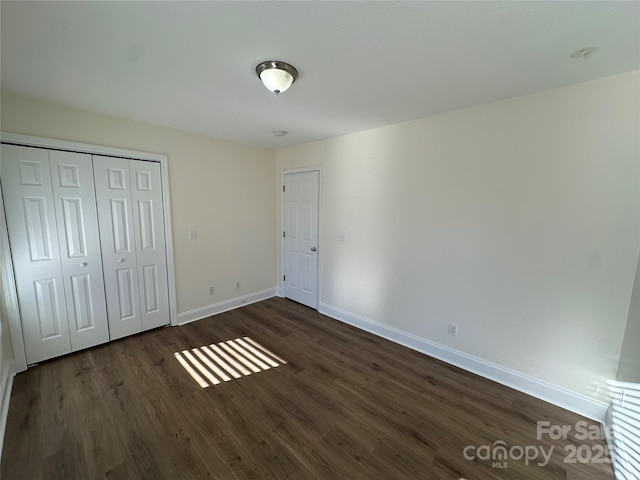 unfurnished bedroom featuring dark hardwood / wood-style floors and a closet