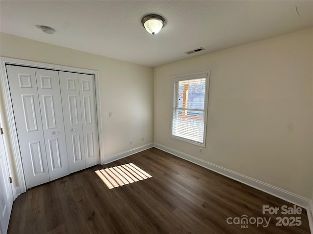 unfurnished bedroom featuring a closet and dark hardwood / wood-style floors