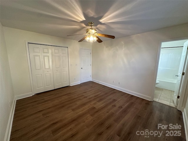 unfurnished bedroom featuring ceiling fan, ensuite bath, and dark hardwood / wood-style floors