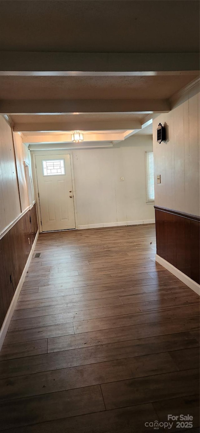 hallway featuring beamed ceiling, hardwood / wood-style floors, and wooden walls