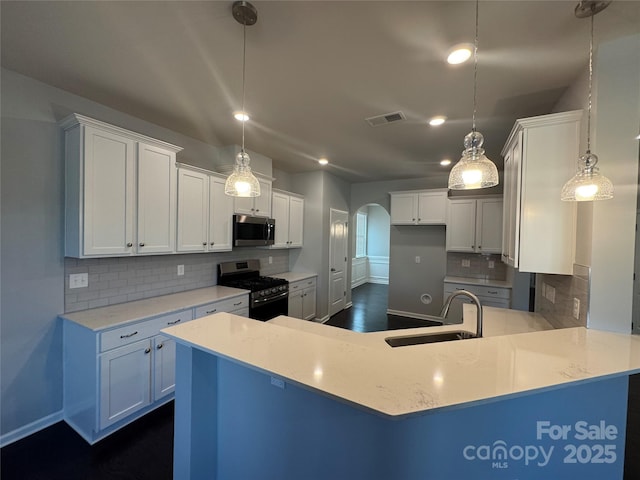 kitchen with appliances with stainless steel finishes, white cabinetry, decorative light fixtures, and kitchen peninsula