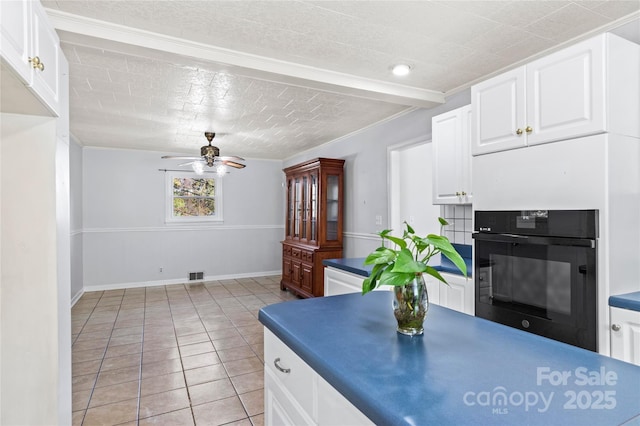 kitchen featuring white cabinets, black oven, ceiling fan, and light tile patterned floors