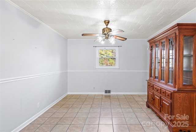 tiled empty room with ceiling fan and ornamental molding