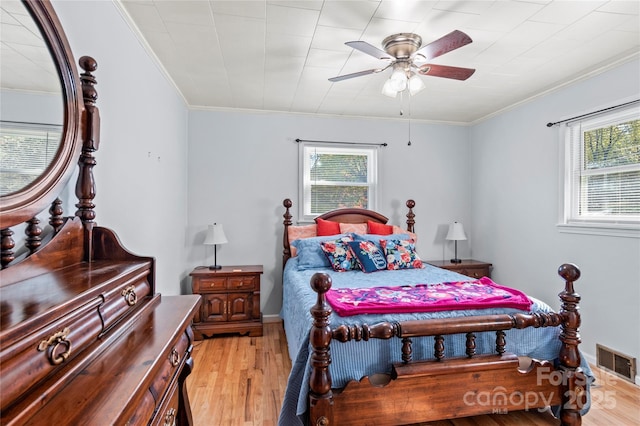 bedroom featuring multiple windows, ceiling fan, light hardwood / wood-style floors, and ornamental molding