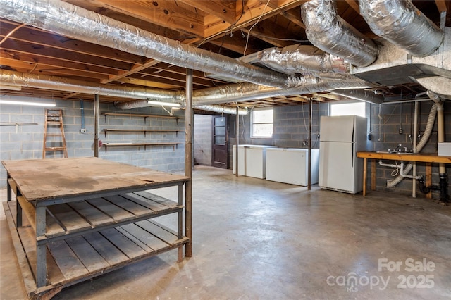 basement featuring independent washer and dryer and white fridge