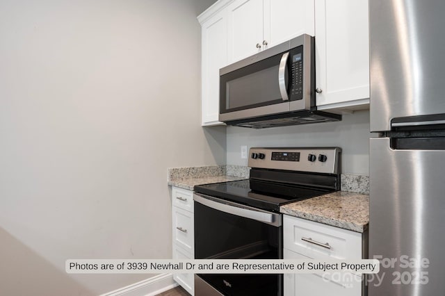 kitchen with white cabinets, light stone counters, and stainless steel appliances