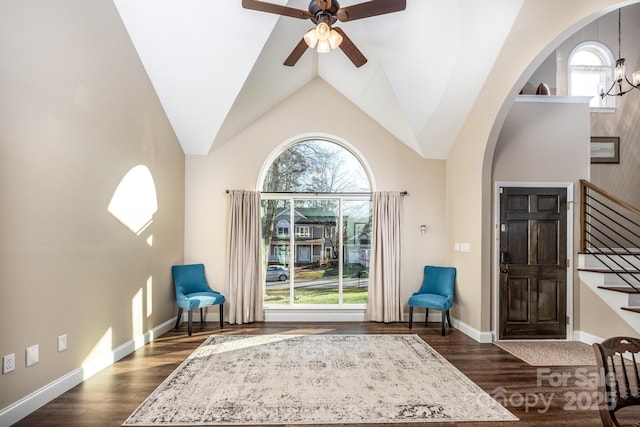 sitting room featuring lofted ceiling, ceiling fan with notable chandelier, and dark wood-type flooring