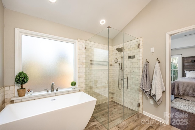 bathroom featuring hardwood / wood-style flooring, shower with separate bathtub, and vaulted ceiling