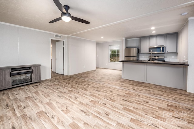 unfurnished living room featuring ceiling fan, crown molding, and light hardwood / wood-style flooring