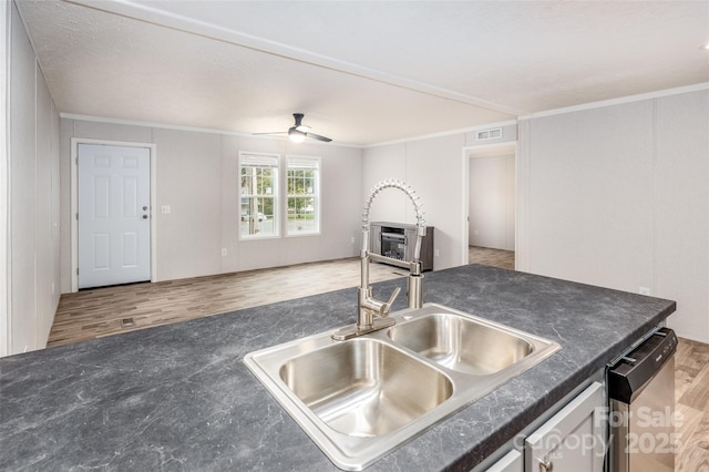 kitchen with hardwood / wood-style floors, stainless steel dishwasher, crown molding, and sink