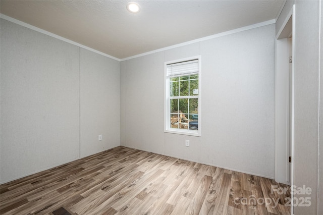 spare room featuring light wood-type flooring and ornamental molding