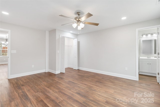 unfurnished bedroom featuring sink, ensuite bath, dark hardwood / wood-style floors, a closet, and ceiling fan with notable chandelier