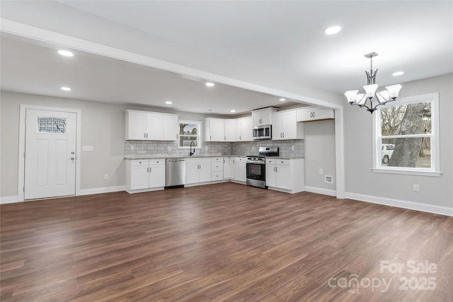 kitchen featuring sink, white cabinetry, decorative light fixtures, stainless steel appliances, and decorative backsplash