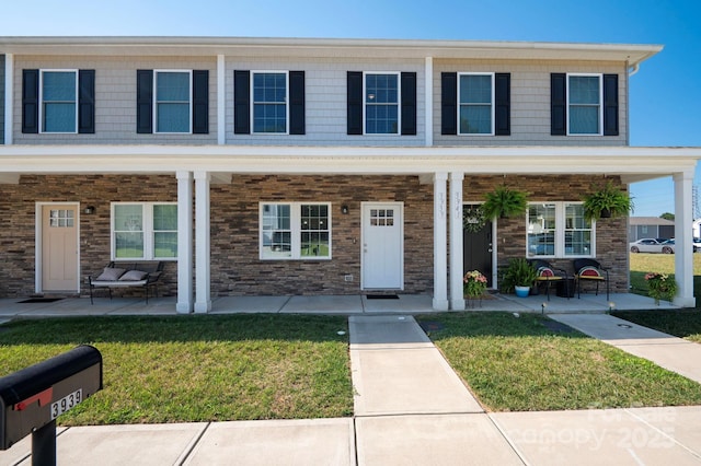 view of property featuring covered porch and a front lawn