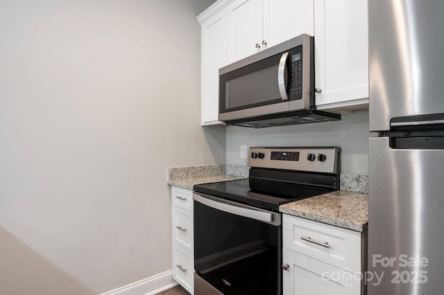 kitchen featuring light stone countertops, stainless steel appliances, and white cabinetry