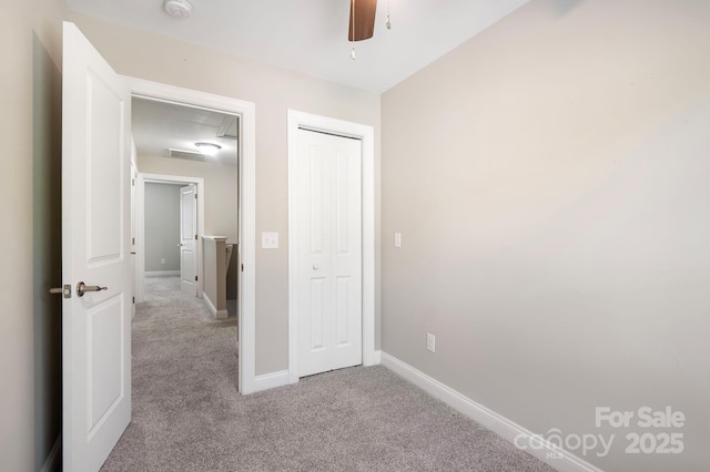 unfurnished bedroom featuring a closet, light colored carpet, and ceiling fan