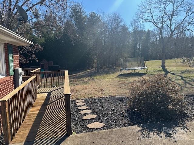 view of yard with a wooden deck and a trampoline