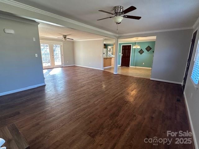 unfurnished room featuring dark hardwood / wood-style flooring, crown molding, ceiling fan with notable chandelier, and french doors