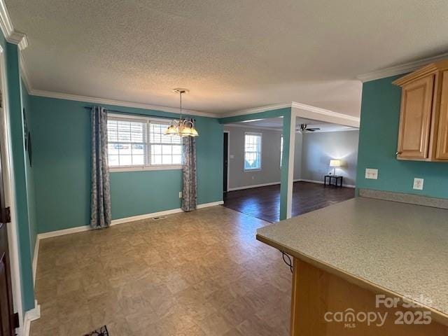 unfurnished dining area featuring a textured ceiling, ornamental molding, ceiling fan with notable chandelier, and plenty of natural light