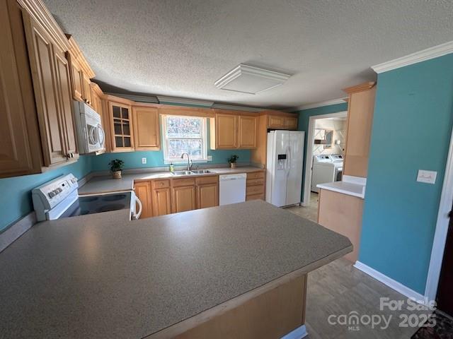 kitchen featuring kitchen peninsula, sink, white appliances, washing machine and clothes dryer, and a textured ceiling