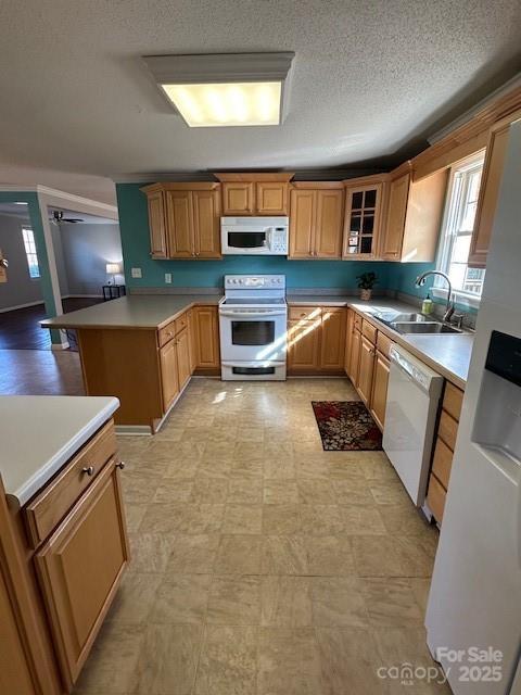 kitchen featuring sink, white appliances, kitchen peninsula, and a textured ceiling