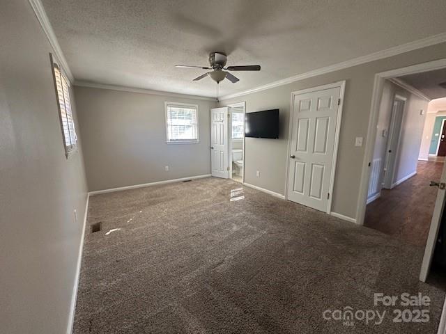 unfurnished bedroom with a textured ceiling, ceiling fan, ornamental molding, and dark carpet