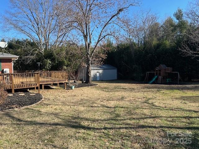 view of yard featuring a playground, a deck, and a shed