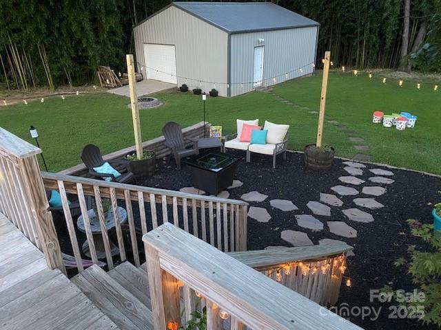 deck with a yard, a garage, a fire pit, and an outdoor structure