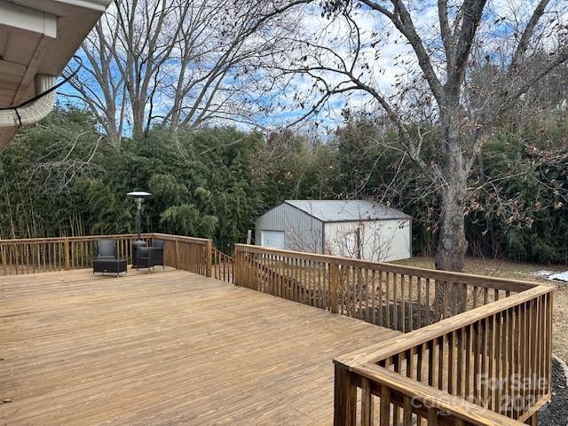 wooden terrace featuring a storage shed and a garage