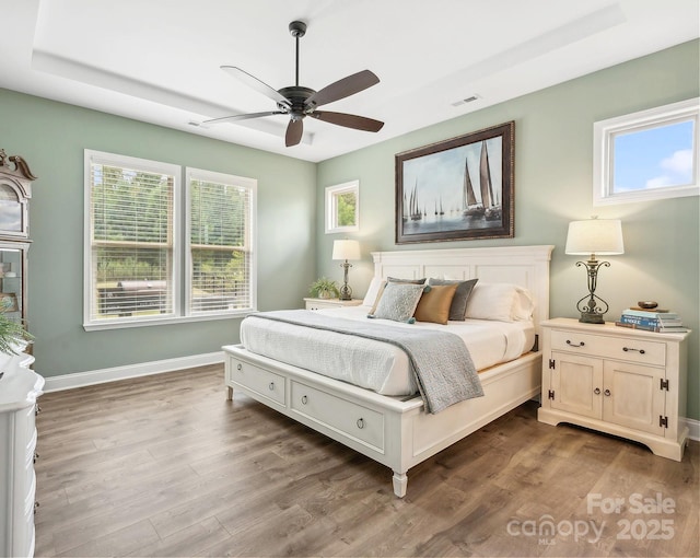 bedroom featuring hardwood / wood-style floors, a tray ceiling, and ceiling fan