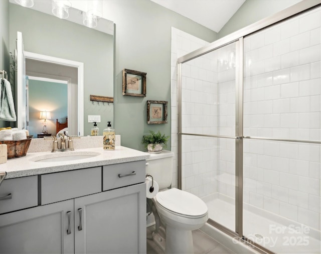 bathroom with vanity, toilet, a shower with shower door, and lofted ceiling